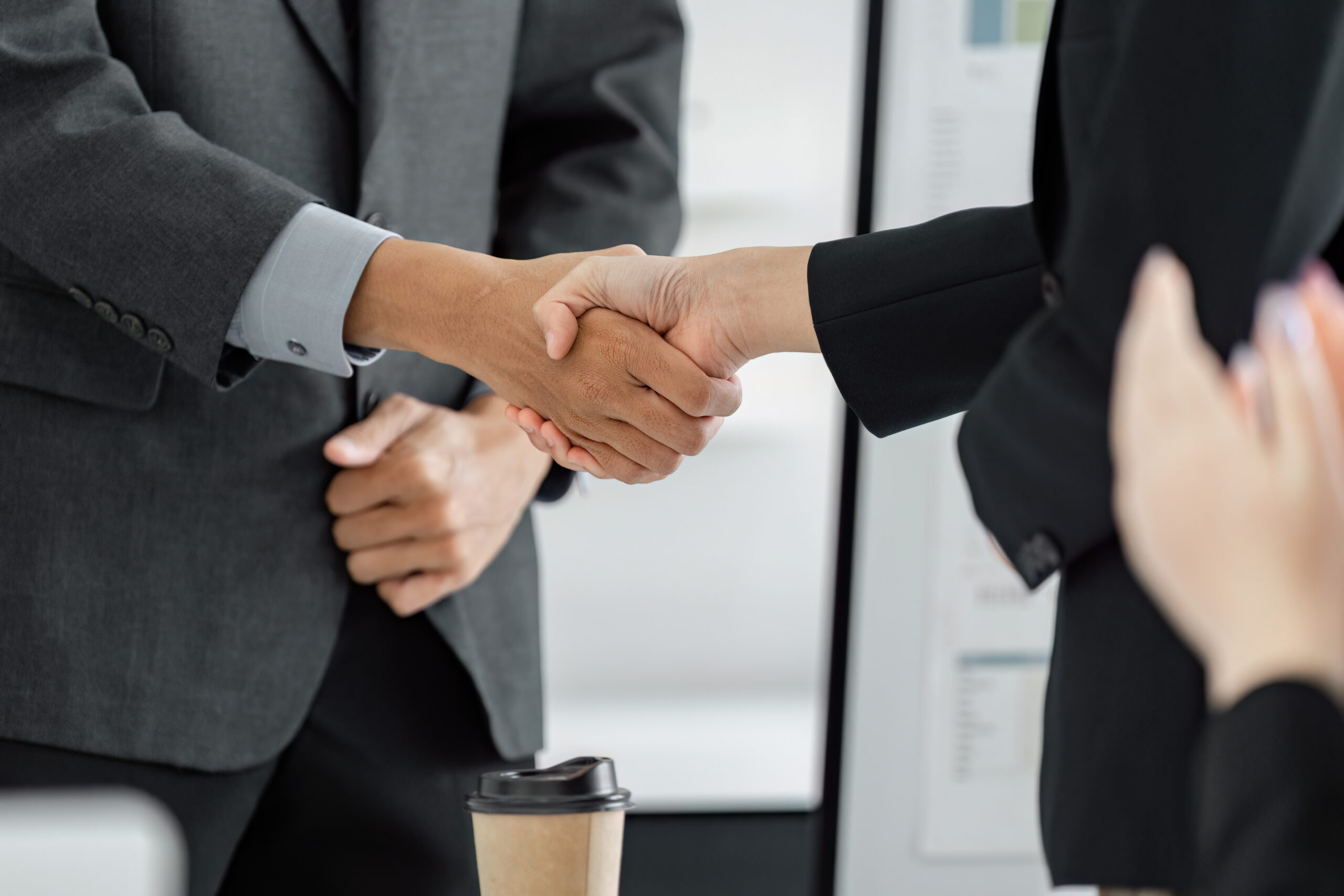 Diverse business professionals shaking hands to finalize a deal in a modern office setting, symbolizing collaboration and successful partnership.